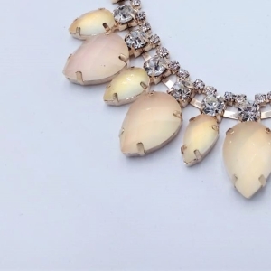 Scollo gioiello, interamente composto da pietre simil cristallo ed effetto madreperla color beige/cipria intarsiate e unite tra loro con basi metalliche oro