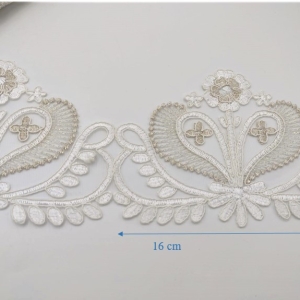 Pizzo 100% poliestere, ricamato su tulle con lavorazione a rebrodè. Modello ritagliabile in modo da ottenere delle applicazioni da abbinare al pizzo. Da 1 metro di pizzo è possibile ricavare 6 applicazioni complete.